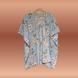 Light blue kimono with white hibiscus floral print, soft silky‑feel fabric, displayed folded on a wooden surface.